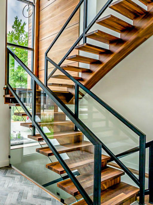 Escalier autoportant à limon central en acier avec marches en erable et garde-corps en verre au style sur-mesure