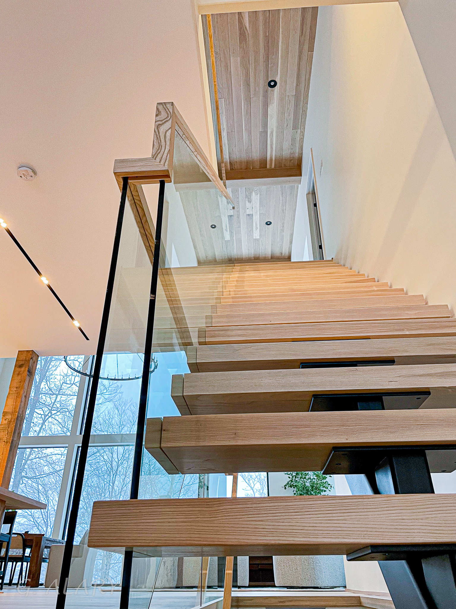 Escalier autoportant à limon central en acier avec marches en meleze et garde-corps en verre au style minimaliste à Saint Sauveur – Escaliers G Alary